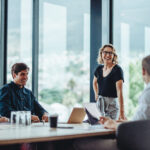 Office colleagues having casual discussion during meeting in conference room. Group of men and women sitting in conference room and smiling.